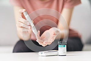 Asian woman using lancet on finger for checking blood sugar level by Glucose meter, Healthcare and Medical, diabetes, glycemia
