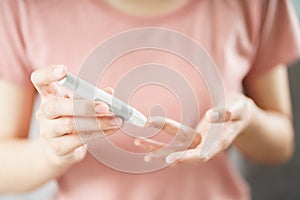 Asian woman using lancet on finger for checking blood sugar level by Glucose meter, Healthcare and Medical, diabetes, glycemia photo