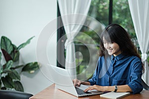 Asian woman using on laptop computer near window at cafe restaurant,Digital age lifestyle,using Technolgy  concept,co working