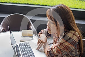 Asian woman using laptop touchpad on coffee table