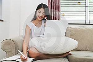 Asian woman using mobile phone and laptop computer work from home