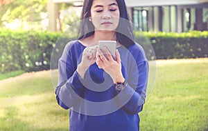 Asian woman using mobile phone outside home in green garden