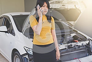 Asian woman using mobilephone with broken down car