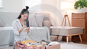 Asian woman using a notebook to review her checklist and packing for a weekend