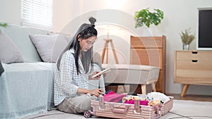 Asian woman using a notebook to review her checklist and packing for a weekend