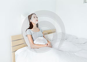 Asian woman using paper mask on face and lying down on the bed