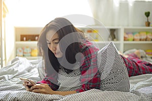 Asian woman using smartphone on bed