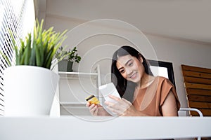 Asian woman using smartphone devices for shopping online in application store and payment by credit card.