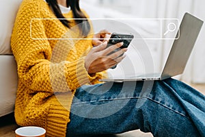 Asian woman using the smartphone, laptop and tablet on the sofa at home