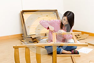 Asian woman using strew driver for assembling furniture