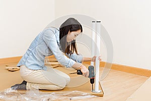 Asian woman using strew driver for assembling furniture