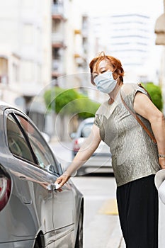 Asian woman using a surgical mask pulling a car door handle while looking at the camera .traveling concept