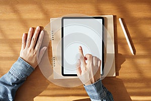 Asian woman using tablet with white screen on hand touchscreen technology item. it put on the desk and notebook