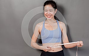 Asian woman using tape to measure her waist