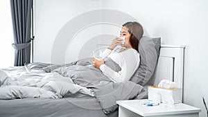 Asian woman using tissue to cough, sneeze and holding a glass of water to take medicine while feeling sick