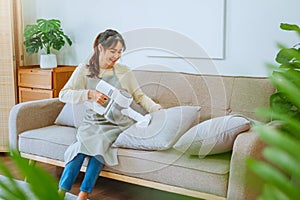 Asian woman using vacuum machine cleaning Sofa. housekeeping concept