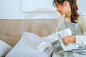 Asian woman using vacuum machine cleaning Sofa. housekeeping concept