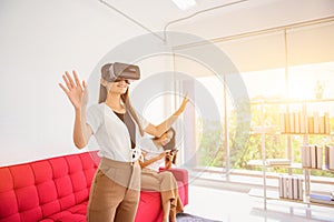 Asian woman using VR headset at home. Wearing virtual reality headset for playing game