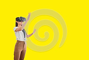 Asian woman using VR headset isolated on yellow background with clipping path. Wearing virtual reality headset for playing
