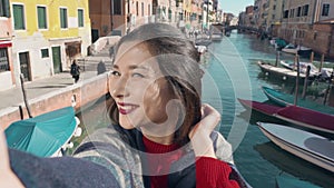 Asian woman in Venice, taking selfie self-portrait photo on vacation travel in Italy. Smiling happy Asian woman outdoors
