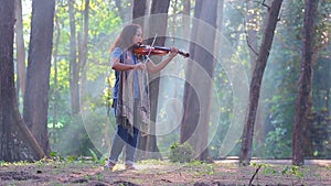 Asian woman with violin in pine forest on sunlight morning