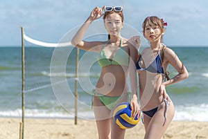 Asian woman volleyball player on the beach with ball on hand