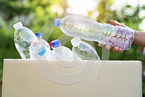 Asian woman volunteer carry water plastic bottles into garbage box trash in park, recycle waste environment ecology concept