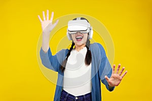 Asian woman in vr glasses isolated yellow background, playing video games with virtual reality headset, Metaverse