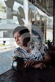 Asian woman waiting in coffee shop cafe with clock