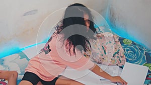 an Asian woman wakes up from her sleep to clean the papers scattered on the bed