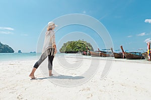 Asian woman walking on the beach and enjoying with beautiful nature in her vacation. Summer holidays and travel concept.