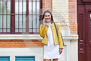 Asian woman walking on the street, wearing cute trendy outfit and talking om her smart phone. City Urban Asian girl talking on her