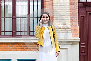 Asian woman walking on the street, wearing cute trendy outfit and talking om her smart phone. City Urban Asian girl talking on her
