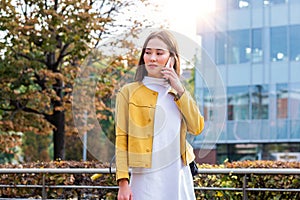 Asian woman walking and using a smart phone in the street in a sunny summer day. Businesswoman talking on her cellphone