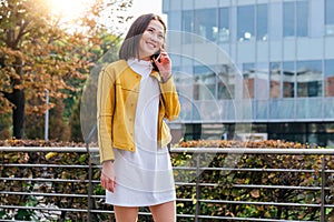 Asian woman walking and using a smart phone in the street in a sunny summer day. Businesswoman talking on her cellphone