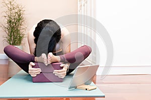 Asian woman warming up and stretching hips flexor with yoga block in bed room at home