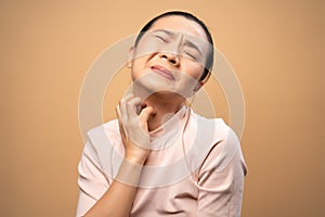 Asian woman was sick with irritate itching her skin standing isolated on beige background photo