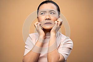Asian woman was sick with irritate itching her skin standing isolated on beige background