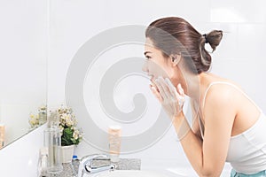 Asian woman wash her face in the bathroom before shower