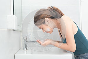 Asian woman wash her face in the bathroom before shower