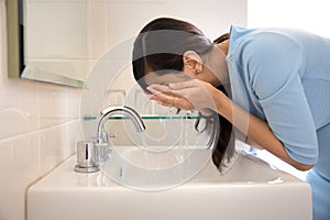 Asian woman washing her face on the sink