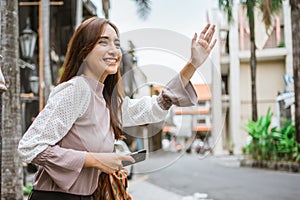 asian woman wave her hand while waiting for taxi