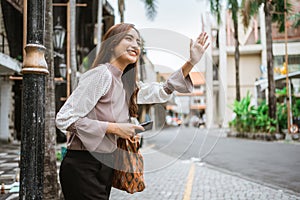 asian woman wave her hand while waiting for taxi