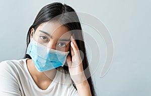 Asian woman wear a face mask are holding their heads because of headaches.She has a fever and migraine because of stress or sleep