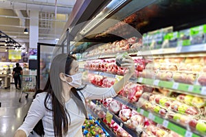 Asian woman wear face mask push shopping cart in suppermarket departmentstore. Girl, looking grocery to buy  fruit. Women wearing