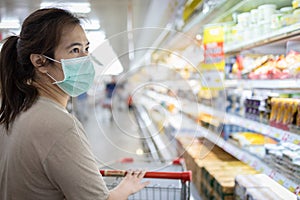 Asian woman wear a mask,looking fresh water and milk,choosing necessary food products,people panic buying and hoarding during the