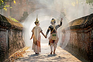 Asian woman wear Thai traditional dress action of walking with holdin hand with Thai classic masked from the Ramakien character as