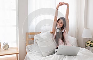 Asian woman wear top tank raise arms up while using laptop on be