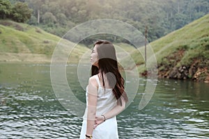 Asian woman wear white dress is smiling near the river in forest. Freedom life in nature.