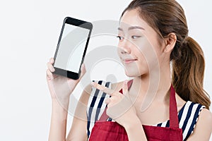 Asian woman wearing apron holding a mobile phone and point her finger to while smiling and happy, Concept using mobiles phone